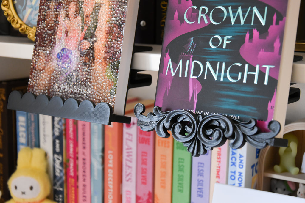 A closeup of the flourish trim in black. Two books are displayed side by side with different decorative trim pieces. one is scalloped and one is a flourish.