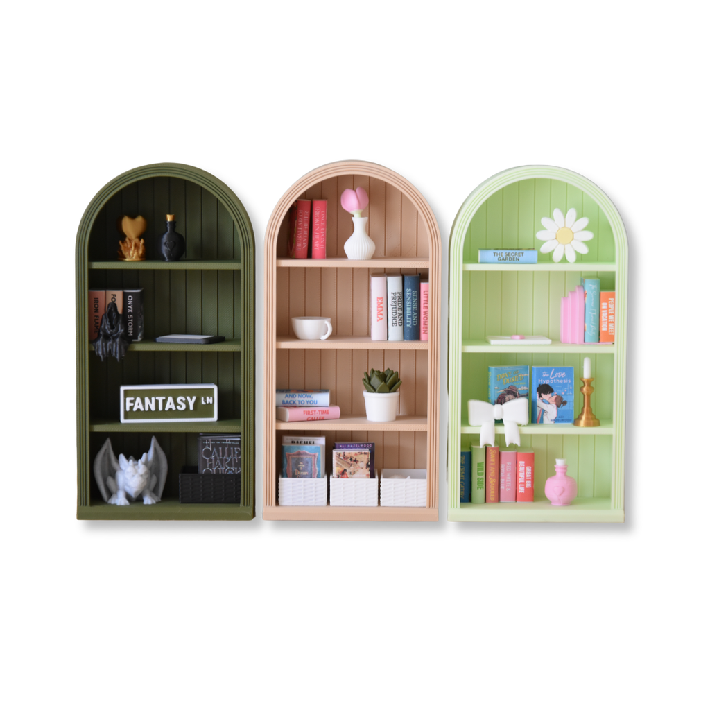 Three arched bookshelves in green, brown, and green with decorative items on a white background.